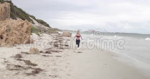 年轻健康的运动女人在海滩上慢跑慢速运动稳定器射击视频的预览图