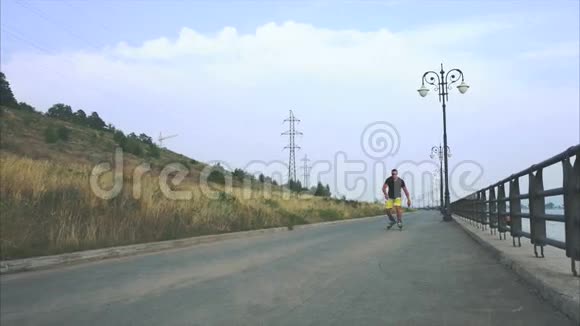 年轻的运动男子与内排滑冰鞋骑和跳跃夏季海滨视频的预览图