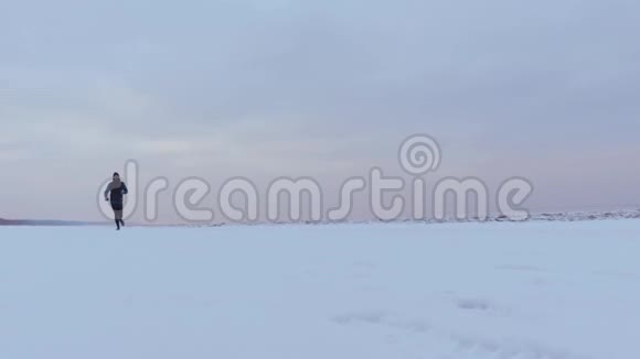 一个冬天在雪地海滩上奔跑的男人视频的预览图