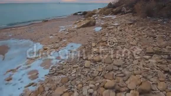在美丽的粉红色日落期间史诗般的飞行无人机飞越冬季海滩4K视频的预览图
