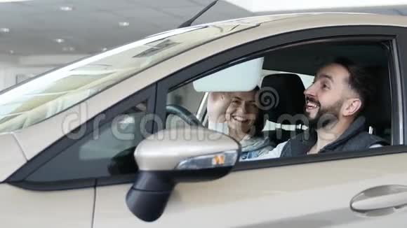 参观汽车经销商漂亮的一家人坐在他们的新车里在说话和微笑年轻人用手指视频的预览图