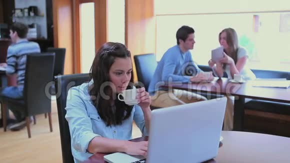 女人一边喝咖啡一边在大学咖啡厅打字视频的预览图
