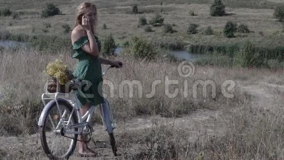一个骑着自行车在路上打电话的年轻女子视频的预览图