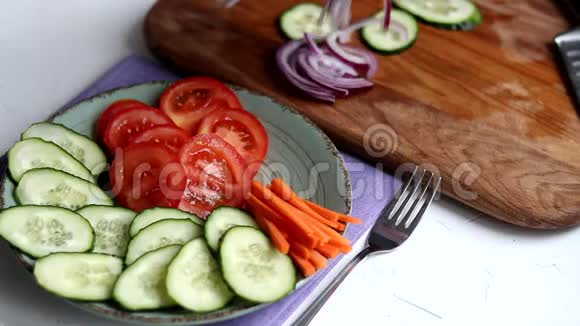 切蔬菜做清淡的沙拉素食健康的饮食西红柿黄瓜胡萝卜和红葱视频的预览图