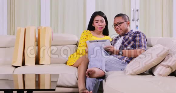 一对夫妇在沙发上用平板电脑购物视频的预览图
