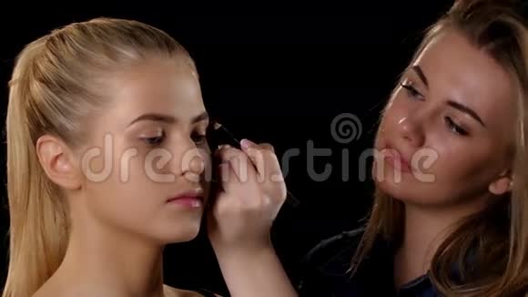 化妆师给金发少女化妆黑色的特写视频的预览图