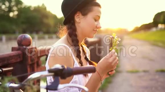 夕阳西下一个年轻漂亮的女人坐在自行车上开着花视频的预览图