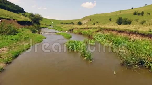 在郁郁葱葱的绿草中在一条缓慢的河流旁欣赏日落美景视频的预览图
