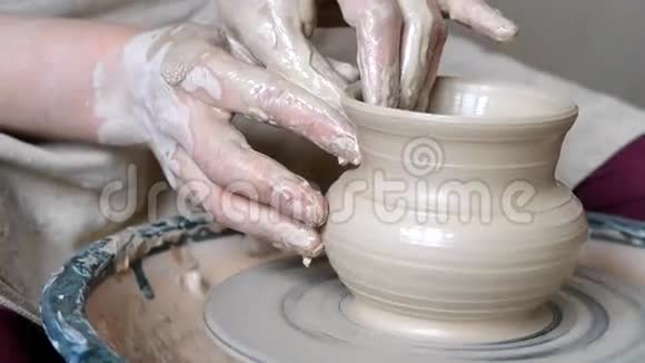 女人用她的双手托起壁壶在圆圈上用粘土雕刻视频的预览图