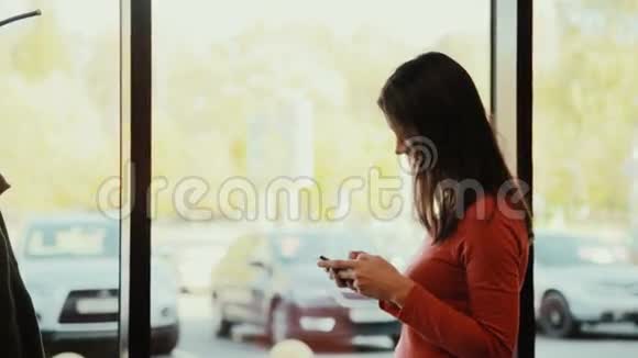 一个年轻的女人在咖啡馆的窗户附近打电话视频的预览图