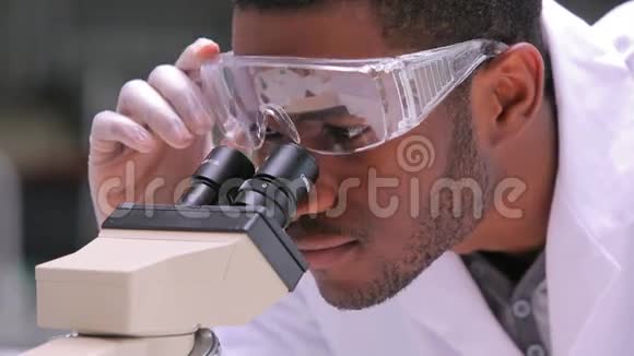 学生举起安全眼镜透过显微镜观察视频的预览图