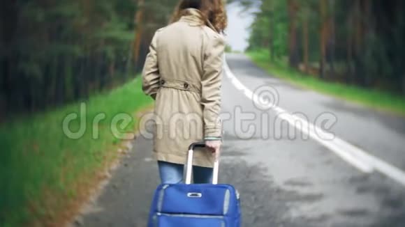 年轻漂亮的女人站在路上一个手提箱放在桌子上上面写着大海视频的预览图