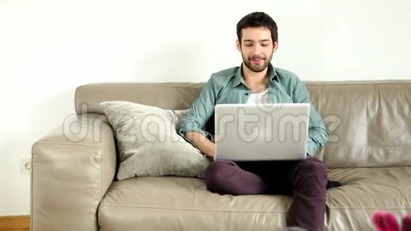 年轻人坐在客厅的沙发上视频聊天视频的预览图