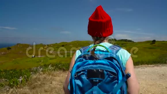 一个背着背包的女人在一片风景如画的山丘上走向大海视频的预览图