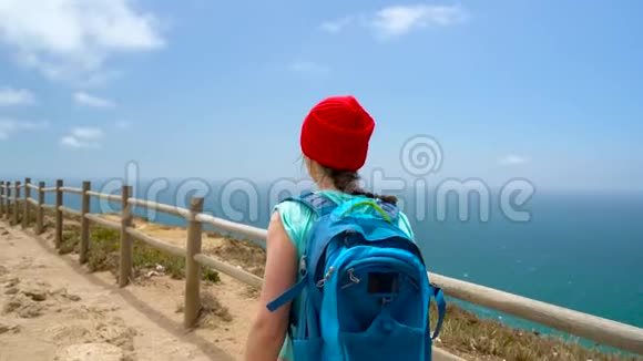 一个背着背包的女人在一片风景如画的山丘上走向大海视频的预览图