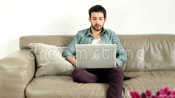 年轻人坐在客厅的沙发上视频聊天视频的预览图