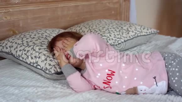 一个穿着睡衣躺在床上的快乐小女孩视频的预览图