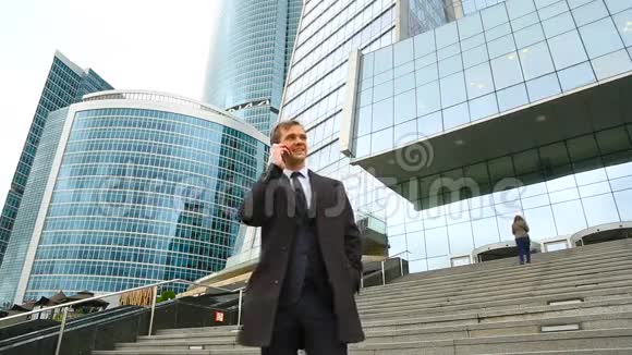 城里的商人用智能手机打电话在摩天大楼的背景下视频的预览图