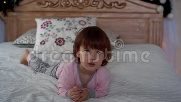 一个穿着睡衣躺在床上的快乐小女孩视频的预览图