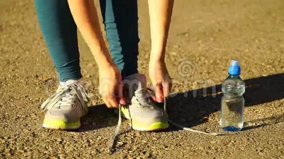 女孩停止跑步把鞋带系在跑鞋上户外健身女孩训练4K视频的预览图