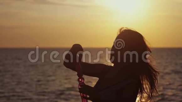 年轻快乐的女人在美丽的夕阳下缓慢地在海滩上吹肥皂泡1920x1080视频的预览图