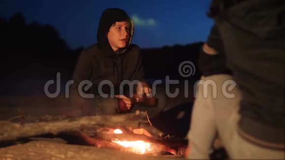 孩子们剪影孩子们坐在火边晚上在篝火旁吃爆米花旅行徒步旅行冒险生活视频的预览图