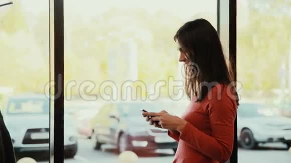 一个年轻的女人在咖啡馆的窗户附近打电话视频的预览图