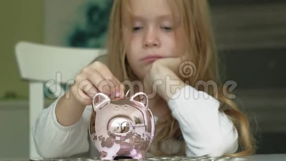 女孩学龄前儿童把钱放在储蓄罐里的粉红猪里视频的预览图