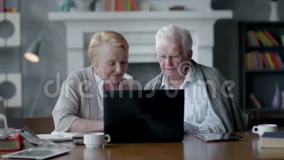网络摄像机一对老夫妇在舒适的客厅里与家人在互联网上交流的乐趣视频的预览图