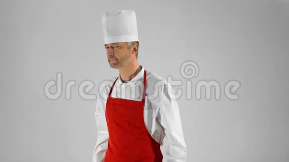 英俊的成年厨师转过身来交叉双臂在灰色背景上点点头视频的预览图
