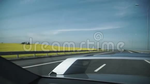 灰车驾驶在黄花田和农田旁的道路上的航摄视频的预览图