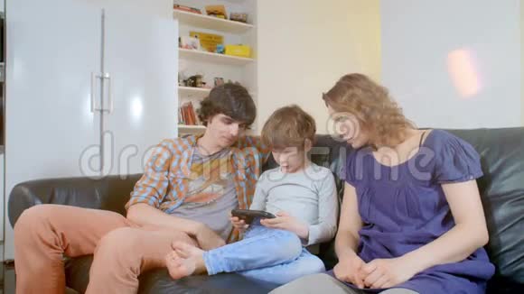 小男孩玩手提游戏机家人饶有兴致地看着他视频的预览图