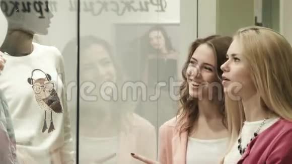 两个女孩看商店的橱窗视频的预览图