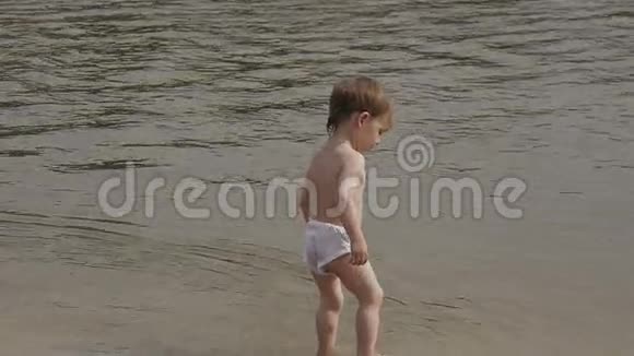 穿着游泳短裤在沙滩上玩耍的小男孩视频的预览图