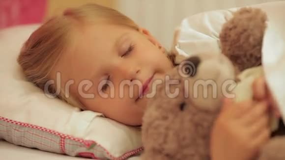 可爱的小女孩和她的玩具熊睡觉视频的预览图