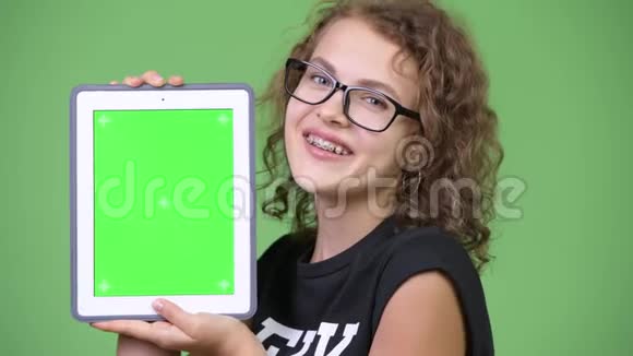 年轻快乐美丽的书呆子女人展示数码平板电脑视频的预览图
