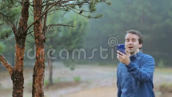 一个人在森林里的一棵树附近通过电话打视频电话清晨视频的预览图