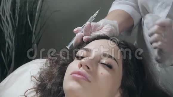 英俊的女人头部受到注射这个程序使医生戴着白手套中间疗法的概念视频的预览图