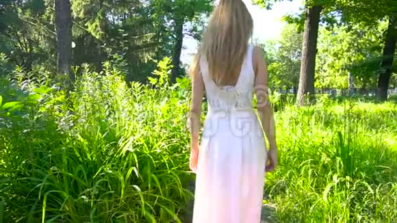穿着裙子在绿色公园散步的女人视频的预览图
