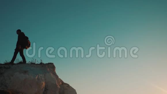 一位男子游客在日落时爬上山顶冒险生活方式冒险的剪影剪影视频的预览图