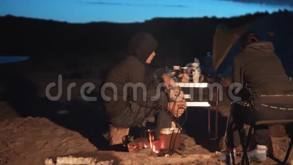 孩子们剪影孩子们坐在火边晚上在篝火旁吃爆米花旅行徒步旅行冒险露营视频的预览图