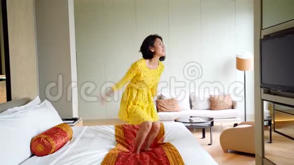 快乐的年轻女人在床上跳跃视频的预览图