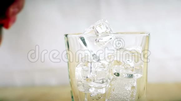 酒吧老板把威士忌倒在杯子里在木桌背景上放冰块专注于冰块威士忌放松时间黄金温暖视频的预览图