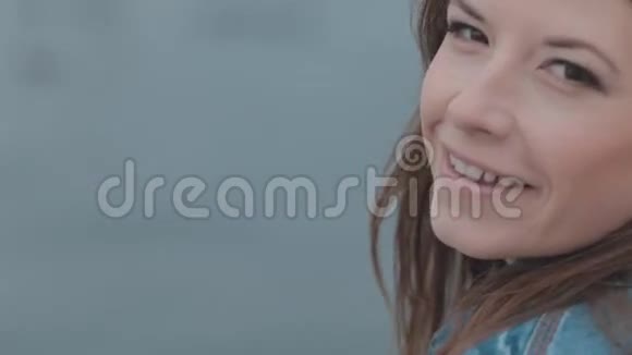 靠近坐在海边的微笑可爱的女孩视频的预览图