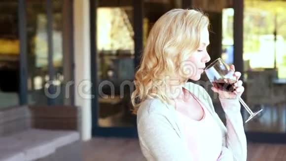 微笑的金发女人站着拿着酒杯视频的预览图