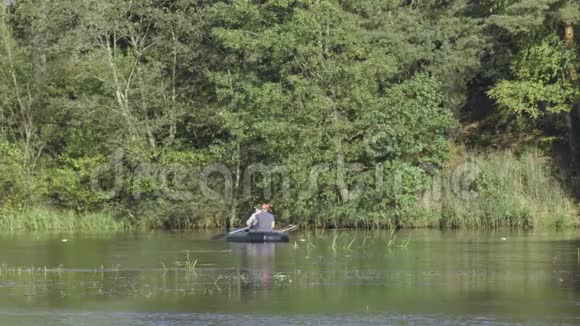 两个穿着橡皮船的渔夫在河上划桨人在阳光明媚的森林里湖上钓鱼斯特拉克河视频的预览图