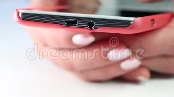 女人在手机上输入短信用红色智能手机靠近女人的手视频的预览图