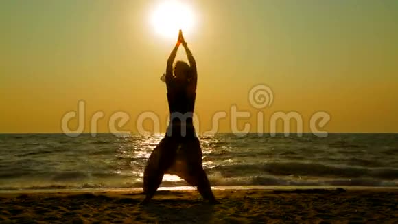 夕阳下沙滩上练习瑜伽的年轻女子视频的预览图