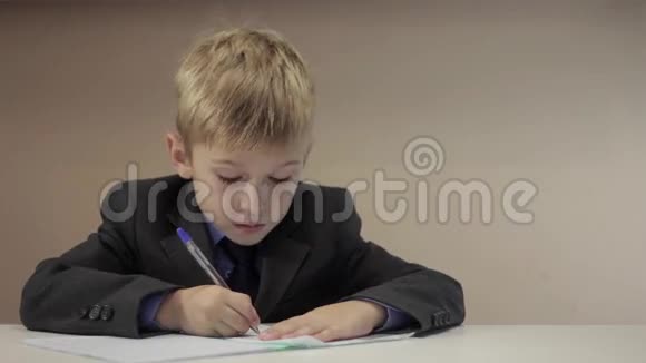 严肃的男孩在笔记本上写字视频的预览图