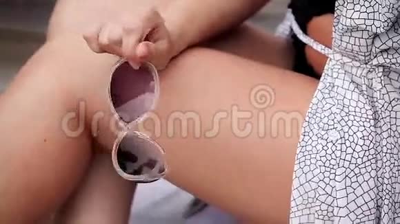 女人手里拿着塑料太阳镜女人穿泳衣外套夏天视频的预览图